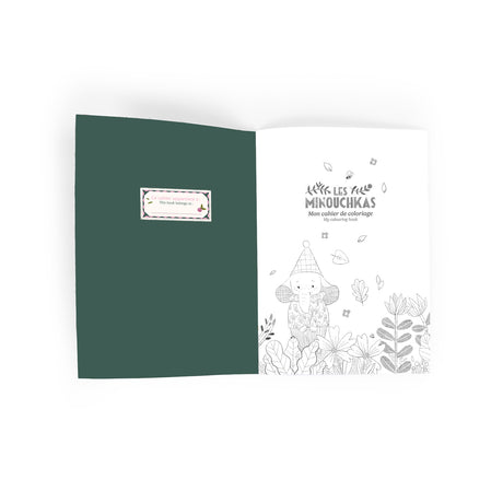 Open coloring book with a dark green left page featuring a text box, alongside a right page with a whimsical elephant illustration and floral designs.