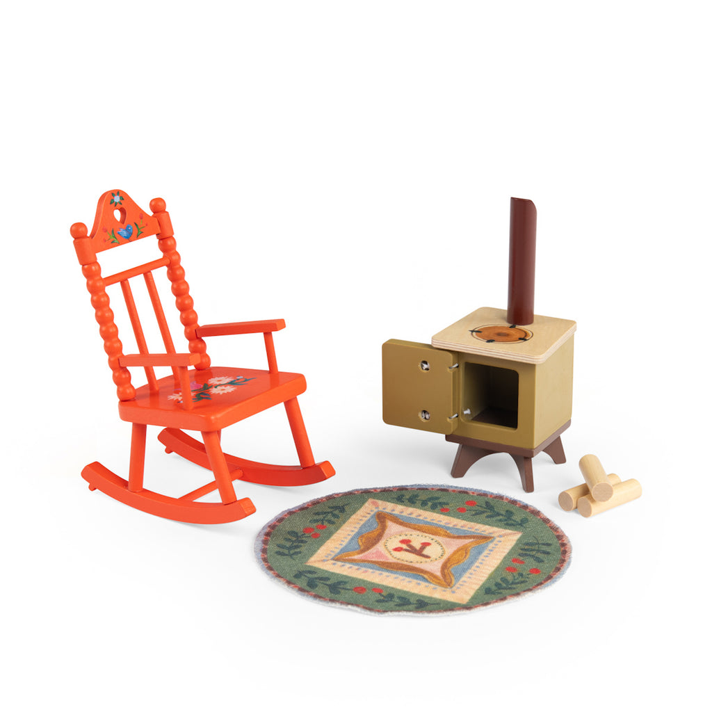 A small, bright orange rocking chair with floral designs, a brown wood stove with an open door, a pile of logs, and a colorful round rug. Cozy atmosphere.