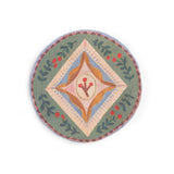 Round folk art coaster with green border, leaves, berries, and a center diamond design.