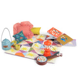 Les Minouchkas fireside accessories with toy lantern, teapot, banjo, books, and colorful quilted play mat.