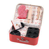 A red suitcase with baking tools, including a rolling pin, whisk, spatula, muffin tray, tart pan, cookie cutters, mitt, and a recipe book.