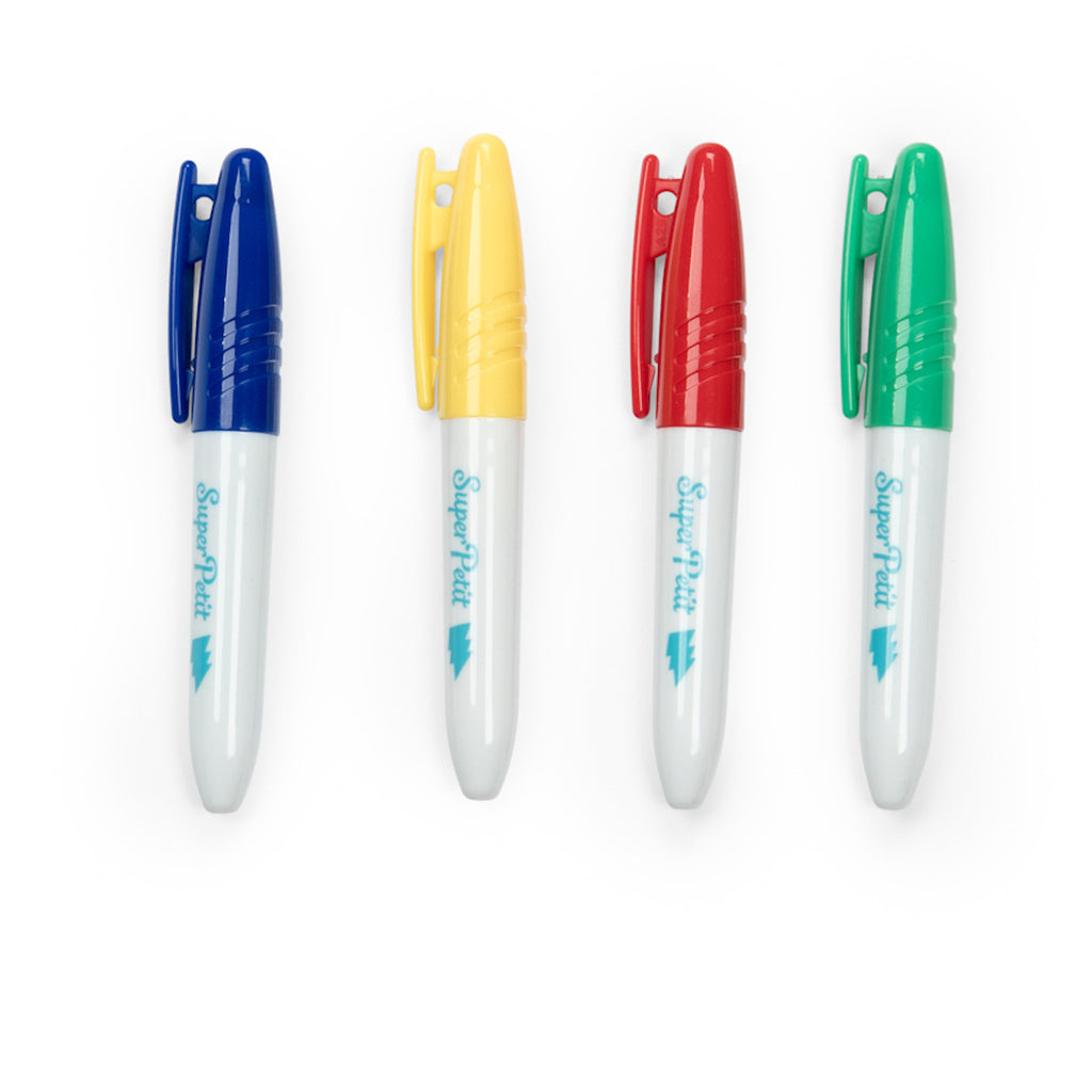 Four white markers with blue, yellow, red, and green caps are aligned horizontally. Each has a clip, creating a vibrant and organized appearance.