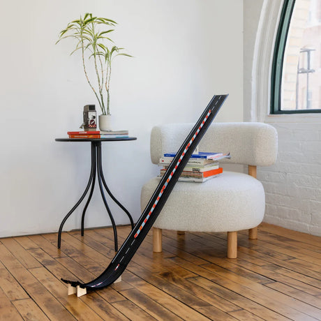 Candylab Super Speed wooden race track ramp in a modern living room with a white chair and hardwood floors.