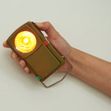 Huckleberry Morse code signal light in use, featuring a hand holding it and the amber light shining.