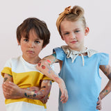 Two kids with serious expressions posing together, showing off colorful temporary tattoos on their arms.