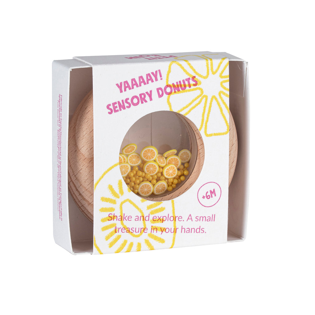 Petit Boum sensory donut in its packaging, with a lemon-themed design and a clear window showing the yellow beads and lemon slices inside."