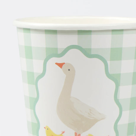 Close-up of a green gingham paper cup featuring a white goose illustration inside a framed border.