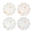 Four wavy-edged paper plates in pastel colors featuring a woodland animal and wildflower pattern.