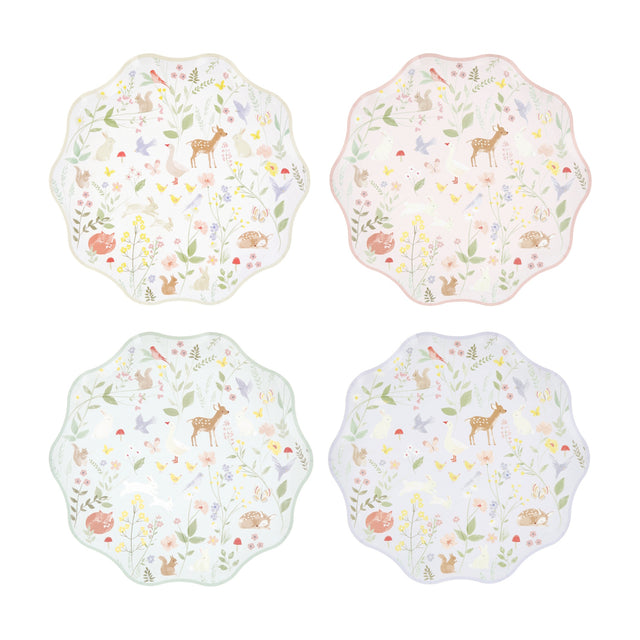 Four wavy-edged paper plates in pastel colors featuring a woodland animal and wildflower pattern.