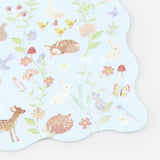 Light blue scalloped napkin with pastel illustrations of woodland animals, birds, flowers, and mushrooms.