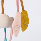 Close-up of plush baby toy charms: a cream cloud and two soft pink and yellow feathers with gold stitching.