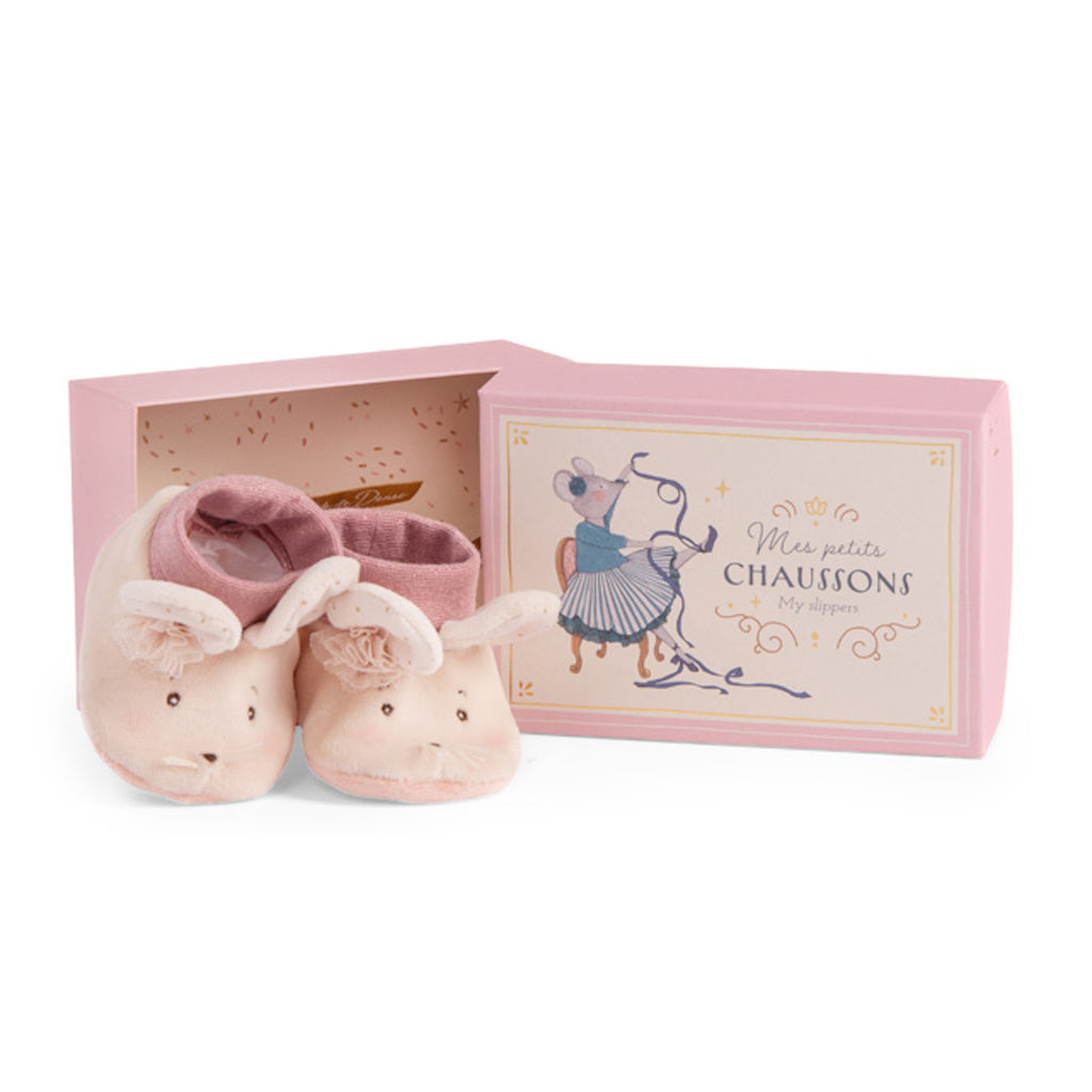 Soft pink baby slippers with mouse faces, ears, and a floral touch sit beside a decorative pale pink box featuring an illustration of a sewing mouse.