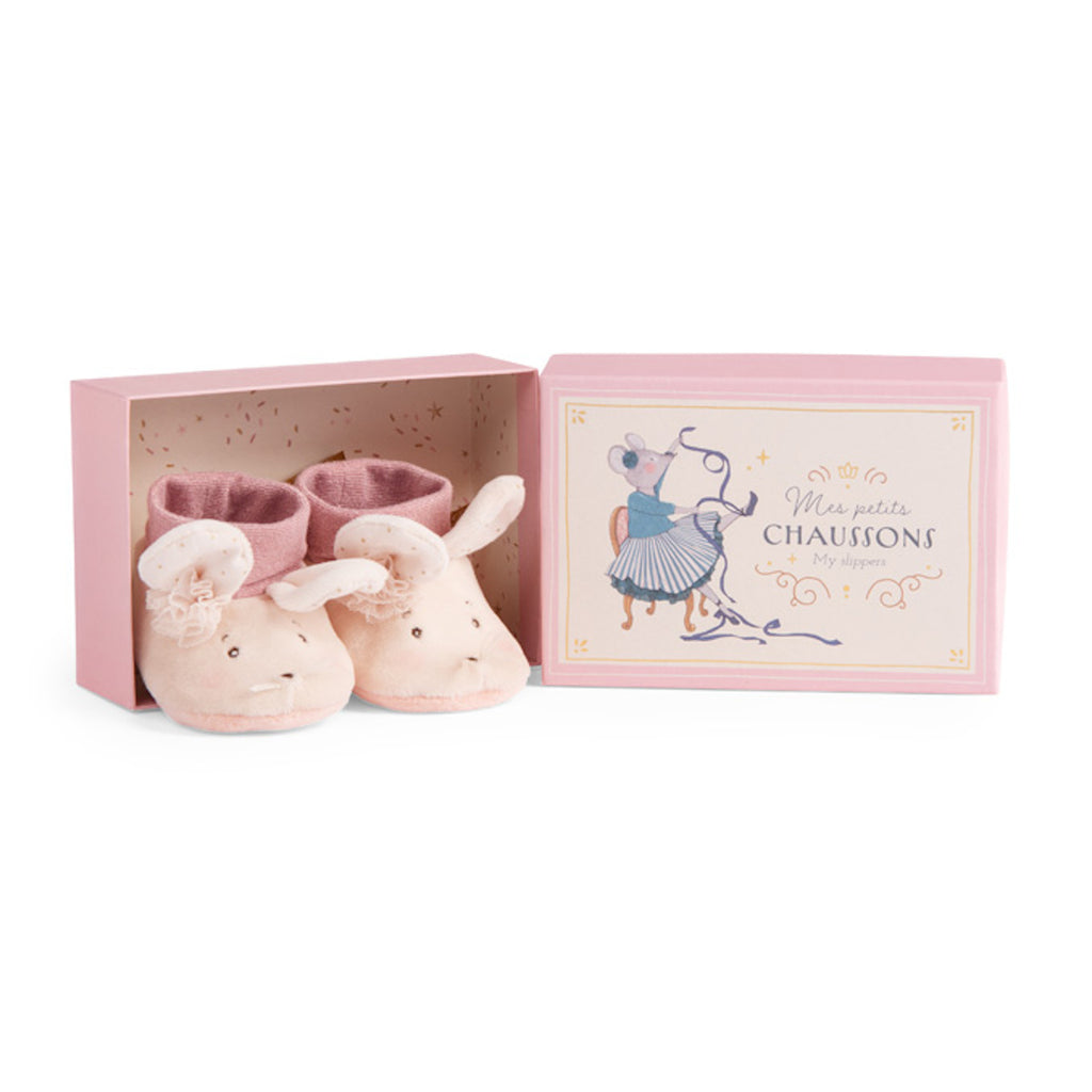 Soft pink baby slippers with mouse faces, ears, and a floral touch sit beside a decorative pale pink box featuring an illustration of a sewing mouse.