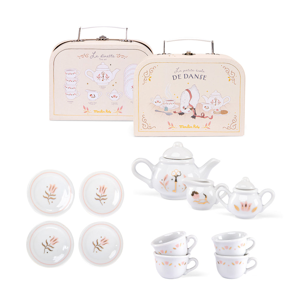 Children's tea set with floral designs, featuring a teapot, creamer, sugar bowl, four cups, and saucers. Two decorative suitcases in the background.