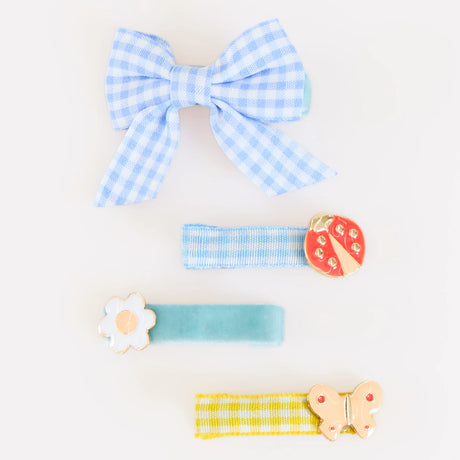 Four blue and yellow patterned hair clips featuring a bow, a ladybug, a flower, and a butterfly.