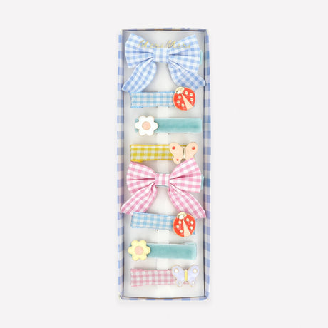 A box of eight assorted hair clips featuring gingham bows, velvet ribbons, ladybugs, flowers, and butterflies.