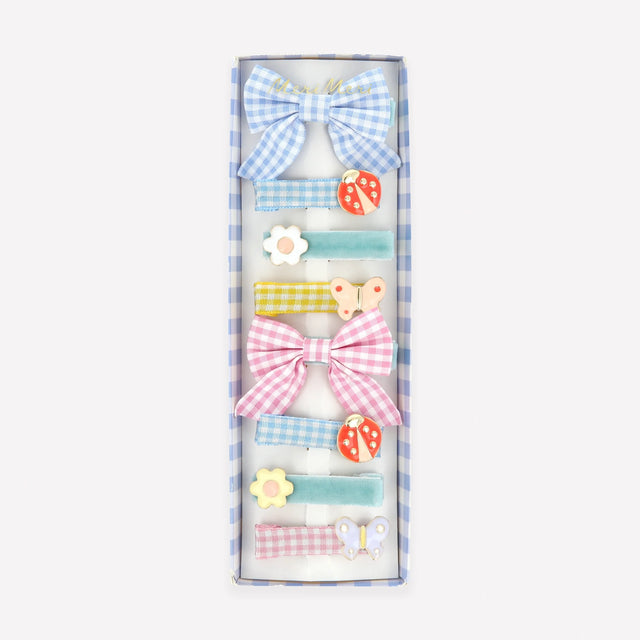 A box of eight assorted hair clips featuring gingham bows, velvet ribbons, ladybugs, flowers, and butterflies.
