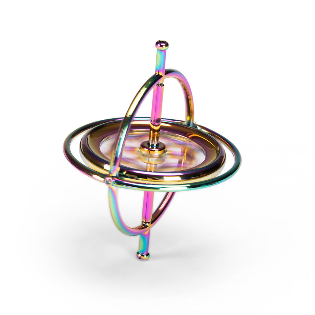 A metallic gyroscope with iridescent colors reflecting pink, blue, and gold hues. It features concentric rings and is set against a white background.