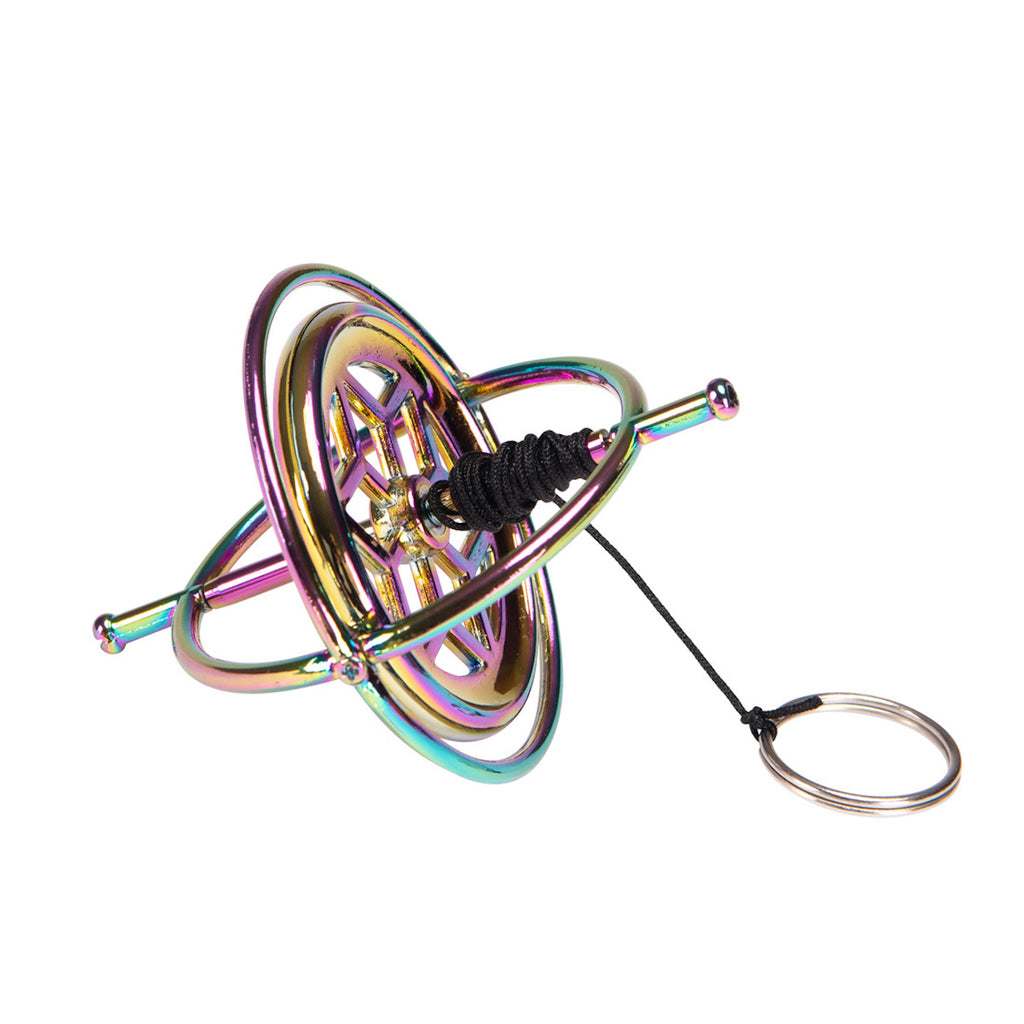 A metallic gyroscope with iridescent colors reflecting pink, blue, and gold hues. It features concentric rings and is set against a white background.