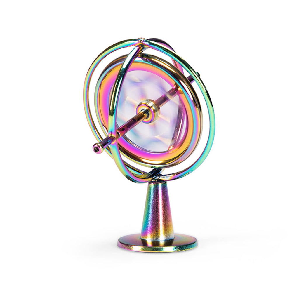 A metallic gyroscope with iridescent colors reflecting pink, blue, and gold hues. It features concentric rings and is set against a white background.