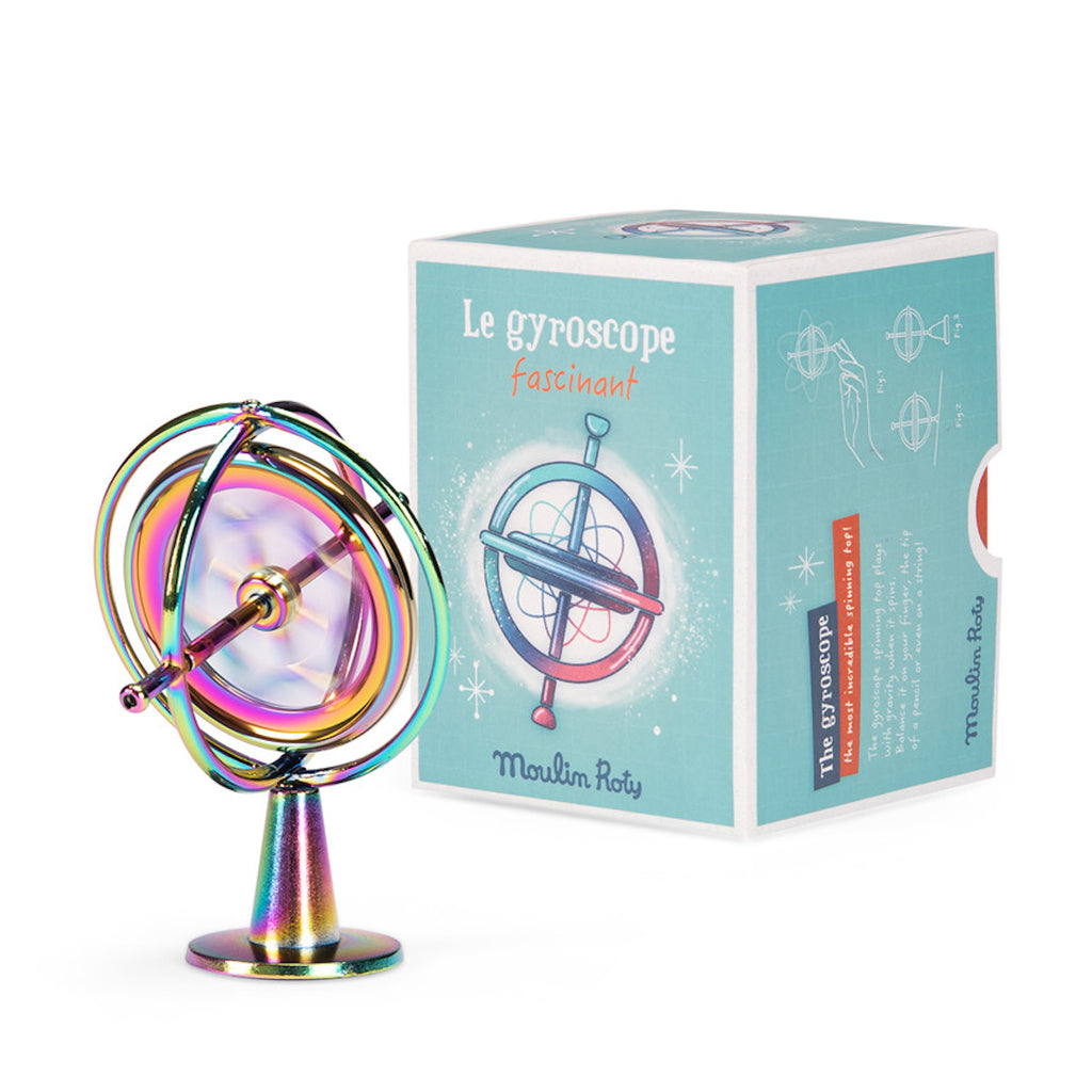 A colorful metallic gyroscope with a string and ring lies beside its blue box featuring an illustrated gyroscope. The tone is playful and nostalgic.