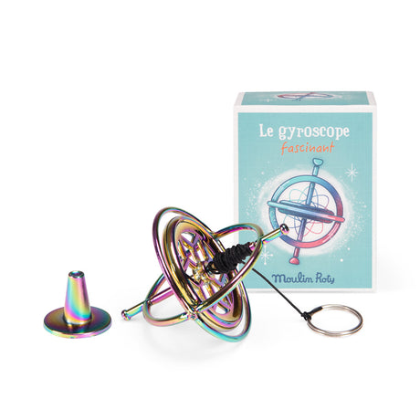 Moulin Roty iridescent metal gyroscope toy with string and stand next to its illustrated blue box.