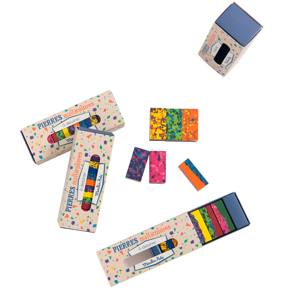 Colorful rectangular art supplies are scattered, featuring vivid patterns in shades of pink, yellow, blue, and green, with matching boxes nearby.