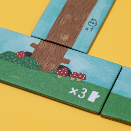Close-up of Londji Piu Piu game tiles showing illustrated mushrooms, a tree trunk, and point multipliers on yellow.