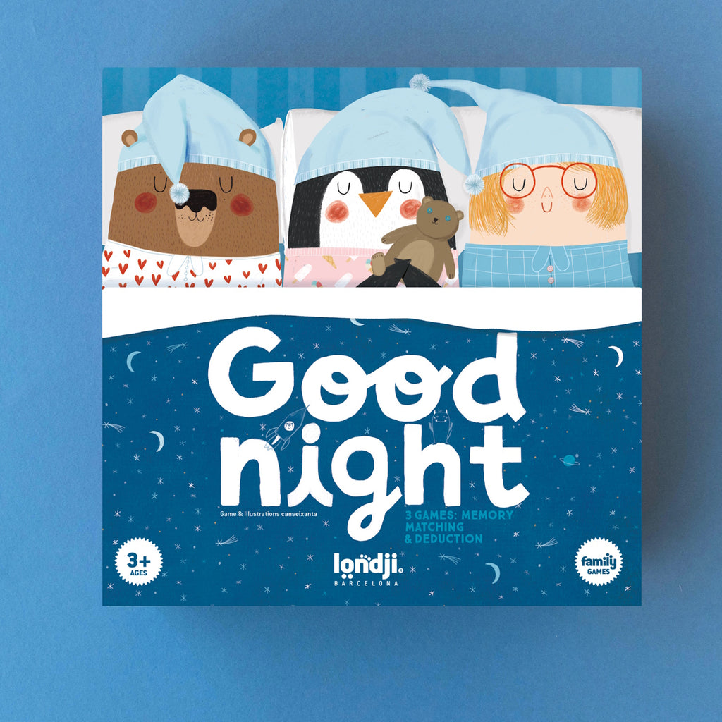 Illustrated game box cover with a bear, penguin, and child in pajamas and blue sleep caps, lying in bed. Text reads "Good night." Playful, cozy tone.