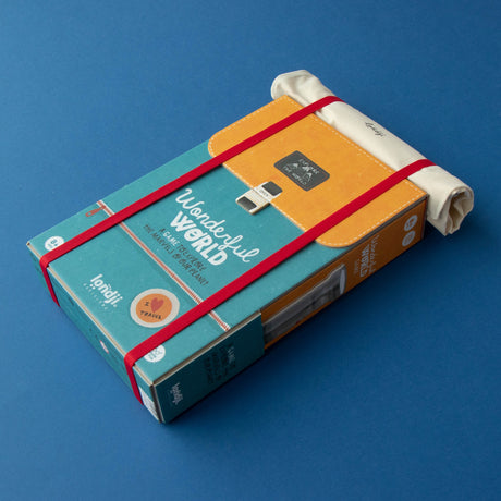 Londji Wonderful World board game in backpack-style packaging with red straps and rolled canvas on blue background.