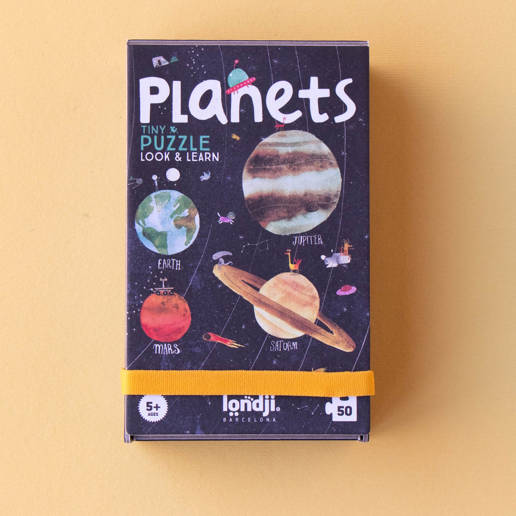 Colorful, educational "Planets" puzzle box for ages 5+, featuring illustrations of Earth, Mars, Jupiter, and Saturn on a dark starry background.
