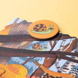 A Londji forest puzzle piece featuring a snail with a hat, with a matching circular snail token placed on top.