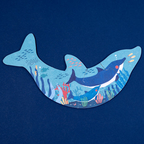 Dolphin-shaped Londji puzzle featuring an underwater scene with whales, coral, and fish on a dark blue background.