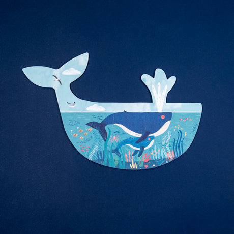 Whale-shaped Londji jigsaw puzzle featuring an underwater scene with whales, fish, and coral on a dark blue background.