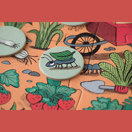 Close-up of a Londji Rabbits Garden puzzle piece and token featuring an ant carrying a leaf in an illustrated garden.