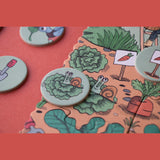 Detailed view of a garden puzzle featuring illustrated snails on lettuce, game tokens, and a carrot sign on a red surface.