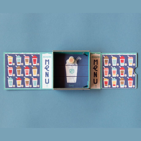 Londji Shakes tiny board game with colorful milkshake menu cards, a wooden die, and a blue illustrated box.