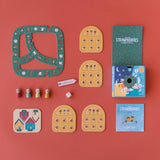 Londji Strawberries Tiny Game components with wooden tokens, cards, and game board on a red background.
