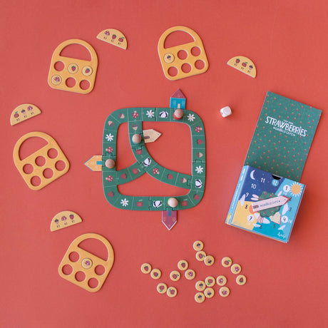 Londji Strawberries Tiny Game with green board, wooden tokens, and yellow baskets on a red background.