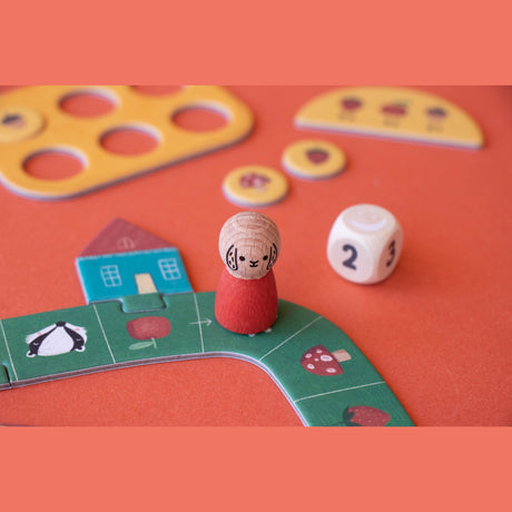 Londji Tiny Game Strawberries featuring wooden dog pawn, dice, and colorful forest-themed game board pieces.