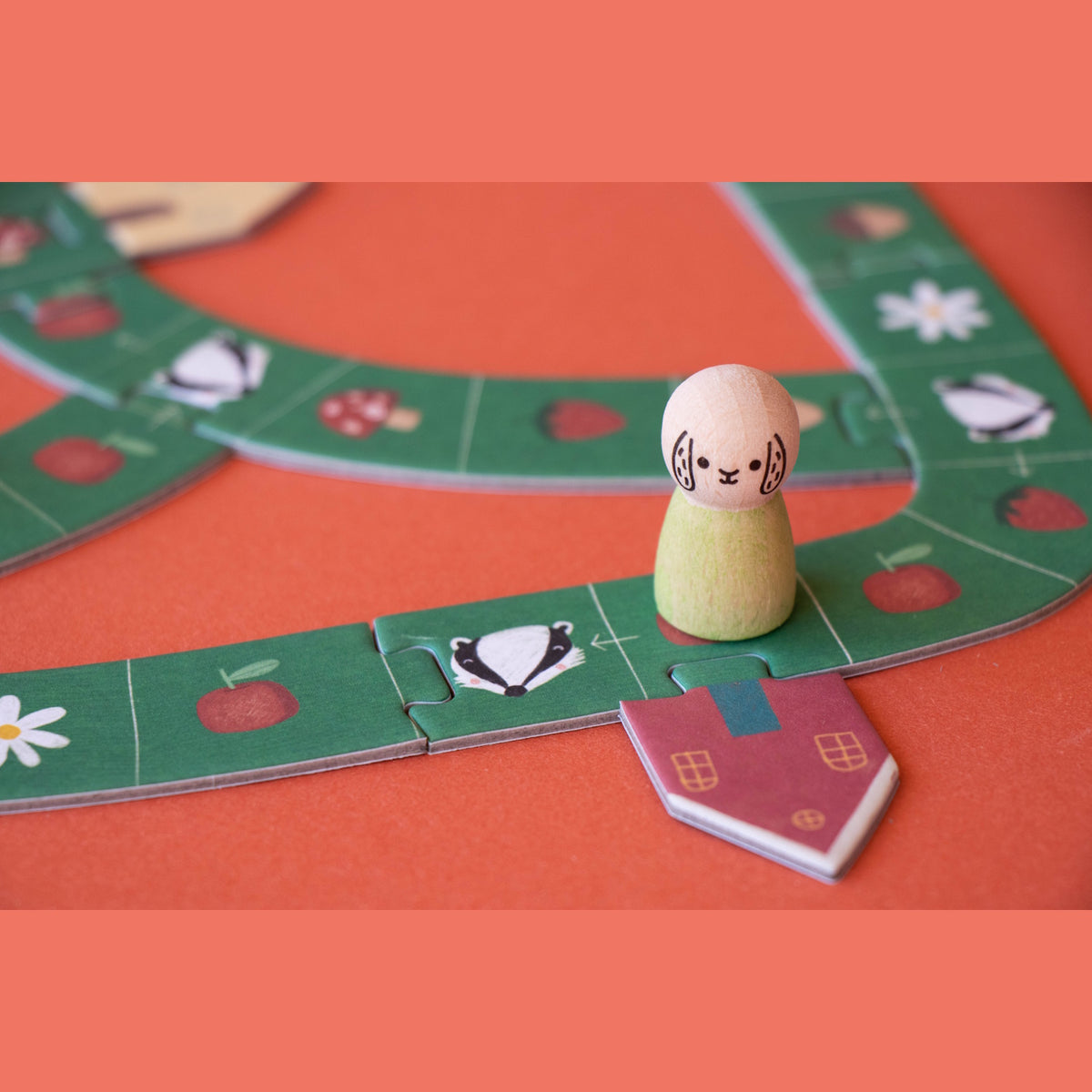 Londji wooden animal peg on a green path board game with badger, strawberry, and apple illustrations.