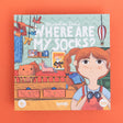 Illustrated game box cover with a girl holding binoculars, toys, and text "Where Are My Socks?" on a patterned background. Whimsical and playful.