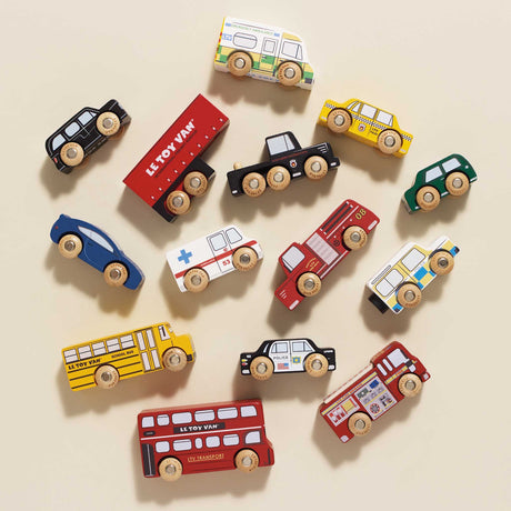Top-down view of various wooden toy vehicles scattered across a beige surface.