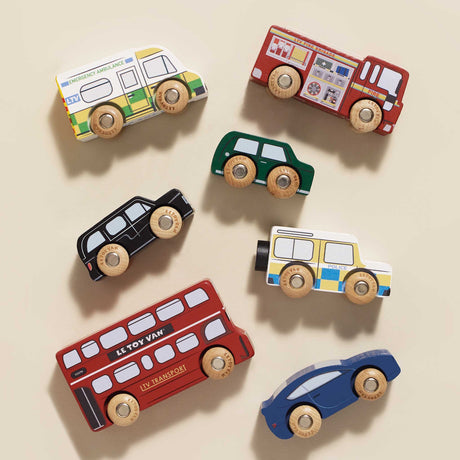 Top-down view of seven wooden London toy vehicles neatly arranged on a beige background.