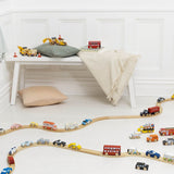 Wooden toy cars arranged on winding tracks across the floor in a bright playroom.