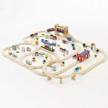 Wooden train track set with mini houses, stations, and a bridge on a white background.