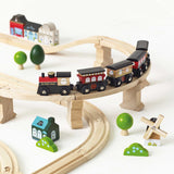 Wooden toy train traveling along an elevated track with miniature buildings and trees.