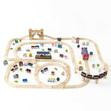 Wooden train set layout with miniature buildings, station, and bridge on a white surface.