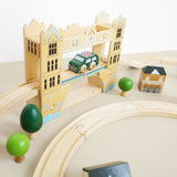 Wooden toy car crossing a Tower Bridge track piece with mini trees and buildings.