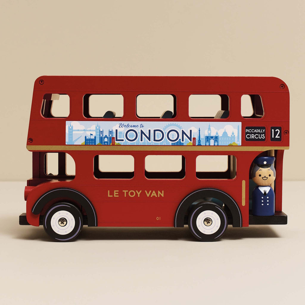 Toy red double-decker bus with a "Welcome to London" sign, featuring a wooden driver figure.